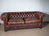 a brown leather couch sitting on a tiled floor