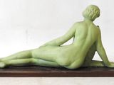 a green sculpture of a woman sitting on a wooden base
