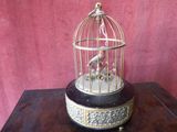 un oiseau dans une cage posée sur une table, sur fond rouge