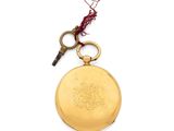 a gold pocket watch with a key on a white background