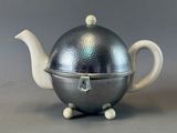 a silver teapot with a silver lid on a table