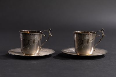 deux tasses et soucoupes en argent posées sur une table