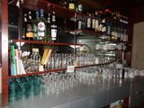 des bouteilles et des verres posés sur une étagère dans un bar où se trouvent de nombreuses bouteilles