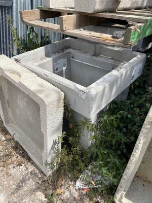 un évier en béton posé au milieu d'un tas de parpaings