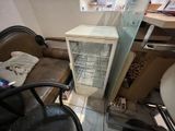 un petit réfrigérateur dans un coin de la pièce, à côté d'une chaise