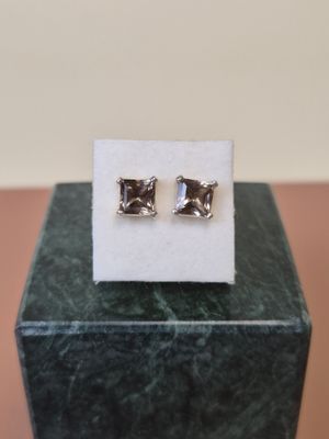 a pair of earrings sitting on top of a marble block