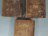 three old books sitting on top of each other on top of a table