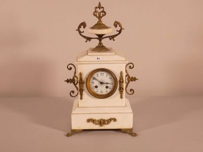 a small white clock with a gold decoration on it