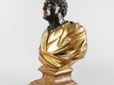 a gold and black bust of a man on a pedestal