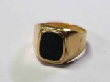 Gros plan sur une bague en or ornée d'une pierre noire