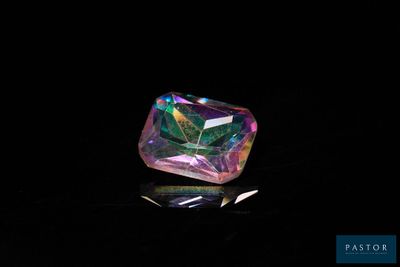 a close up of a colorful diamond on a black surface