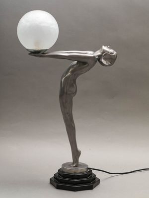 sculpture représentant une femme tenant une boule de verre posée sur une table