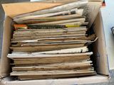 une boîte en carton remplie de journaux, posée par terre