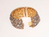 an image of a gold and diamond cuff bracelet on a white surface