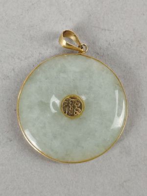 a close up of a gold plated pendant on a white surface