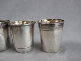 three silver shot glasses sitting next to each other on a table