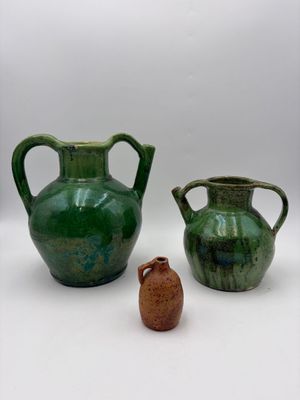 two vases sitting next to each other on a white surface