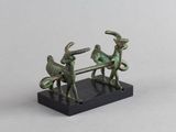 une figurine en bronze représentant deux hommes assis sur un banc