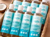 un panier contenant six flacons de produits pour le bain, posé sur une table en bois