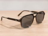 sunglasses on a wooden table with a white wall in the background
