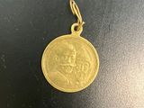 une pièce d'or sur laquelle est représenté un visage, posée sur une surface noire