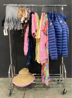clothes hanging on a rack with a hat on top of it