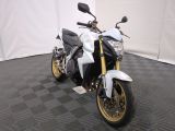 une photo d'une moto blanche et noire garée sur un sol à damier noir et blanc