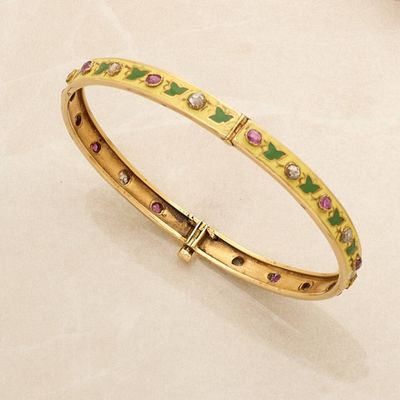 a close up of a gold bracelet with pink and green stones