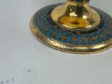 a gold and blue candle holder on a white table