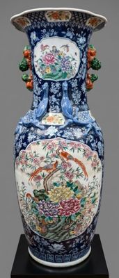 a vase with a bird and flowers on it on a stand