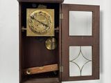 a clock in a wooden case with a mirror on the wall