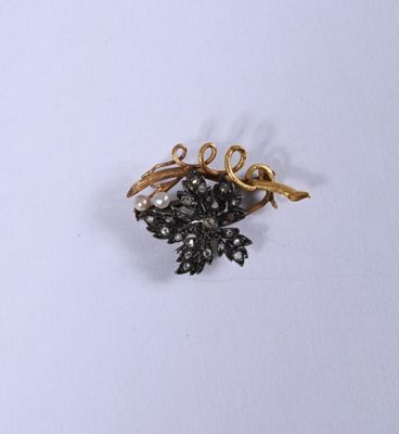 une broche en forme de fleur noire et dorée sur un fond blanc
