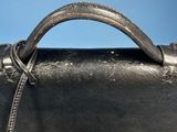 a close up of a black leather bag with a metal handle