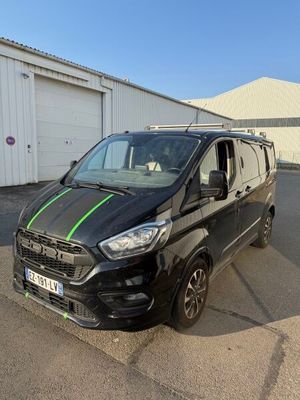 une camionnette noire avec des bandes vertes garée devant un immeuble