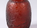 a red glass vase with a leaf design on it