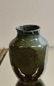 a small green vase sitting on a glass table