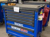 La boîte à outils bleue se trouve dans le garage avec d'autres outils.