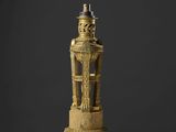 une statue en or représentant un homme sur un socle, surmontée d'un oiseau