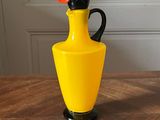 un vase jaune surmonté d'un oiseau noir