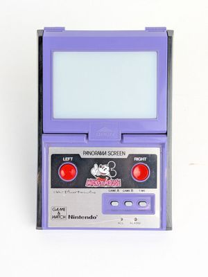 une vieille Game Boy avec un boîtier violet posée sur une surface blanche