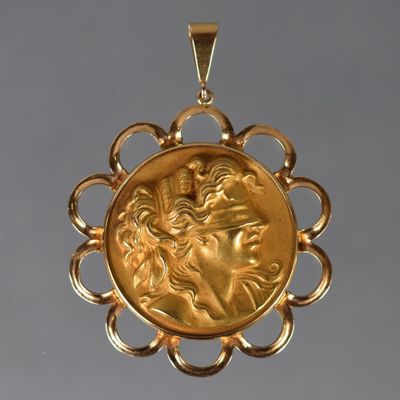 une image représentant un pendentif en or avec le visage d'une femme au centre