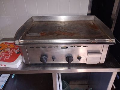 un plan de travail en acier inoxydable surmonté d'une plaque de cuisson, dans une cuisine