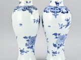 pair of blue and white vases with flowers and vines on them