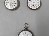 three different types of pocket watches are displayed on a table