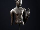 une statue en bronze représentant un Bouddha assis sur un fond noir