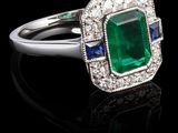 un gros plan d'une bague sertie d'une émeraude verte et de saphirs bleus
