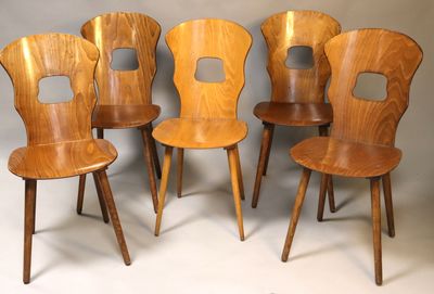 quatre chaises en bois sont alignées contre un mur gris
