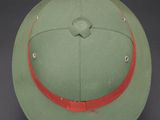 an army green hat with a red band on a black background