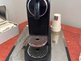 a black coffee machine sitting on a counter next to a cup