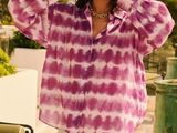 the woman is wearing a purple tie dye shirt and a white plea skirt